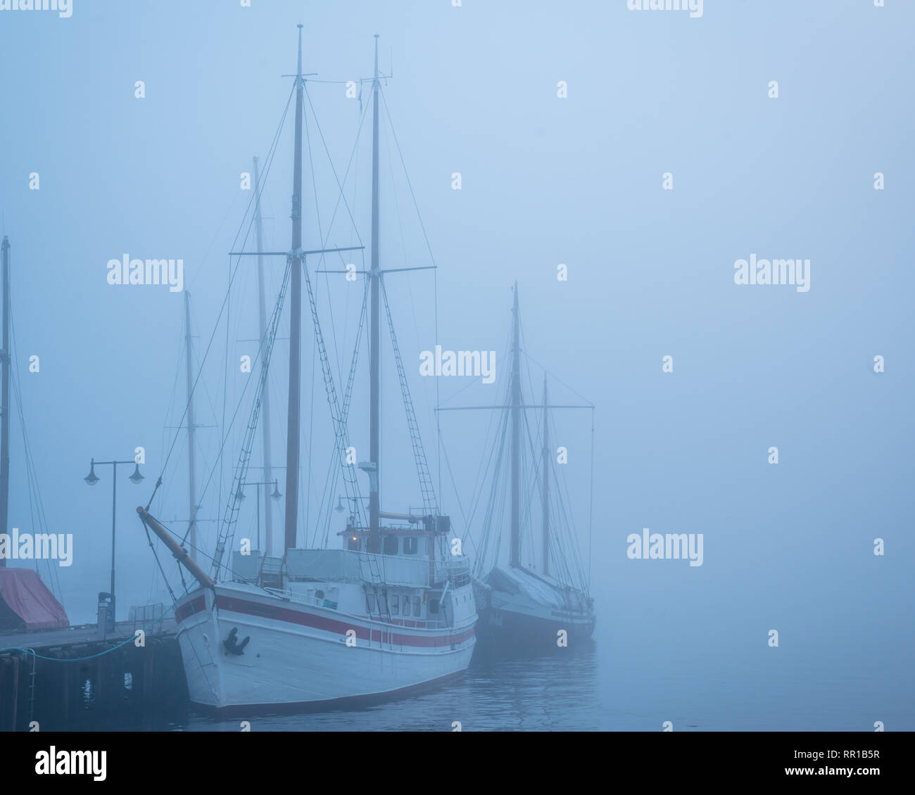 Misty romantische Segel Boote ohne Segel im Wasser in der Nähe von einem Dock Stockfoto