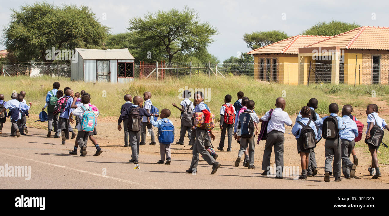 Masse der Grundschüler zu Fuß von der Schule nach Hause am Nachmittag in ihren Schuluniformen in der North West Provinz, Südafrika gekleidet Stockfoto