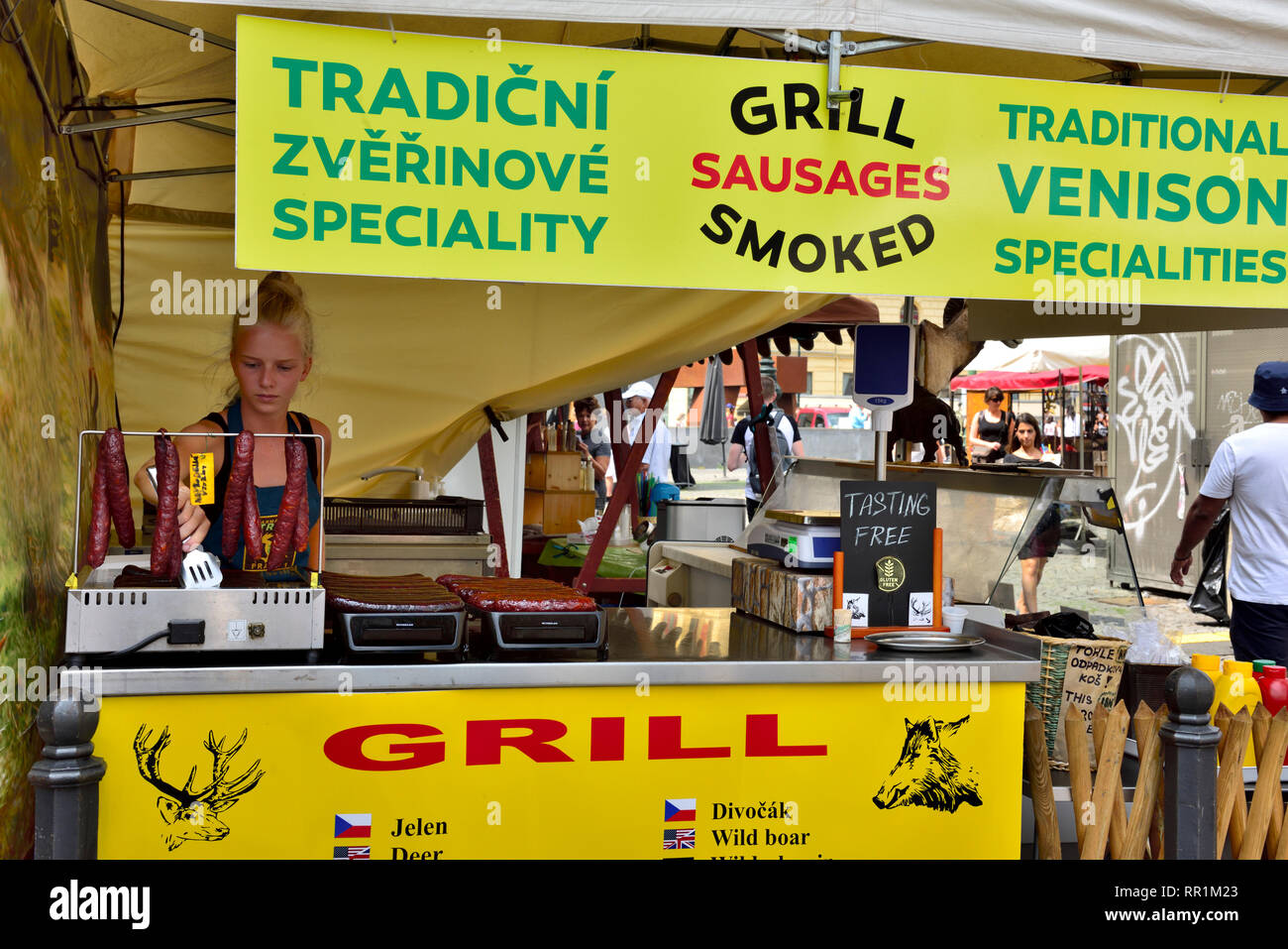 Junge Frau Standbesitzer mit traditionellen gegrilltem Wildbret Würstchen bei Farmers Market, Prag, Tschechische Republik Stockfoto