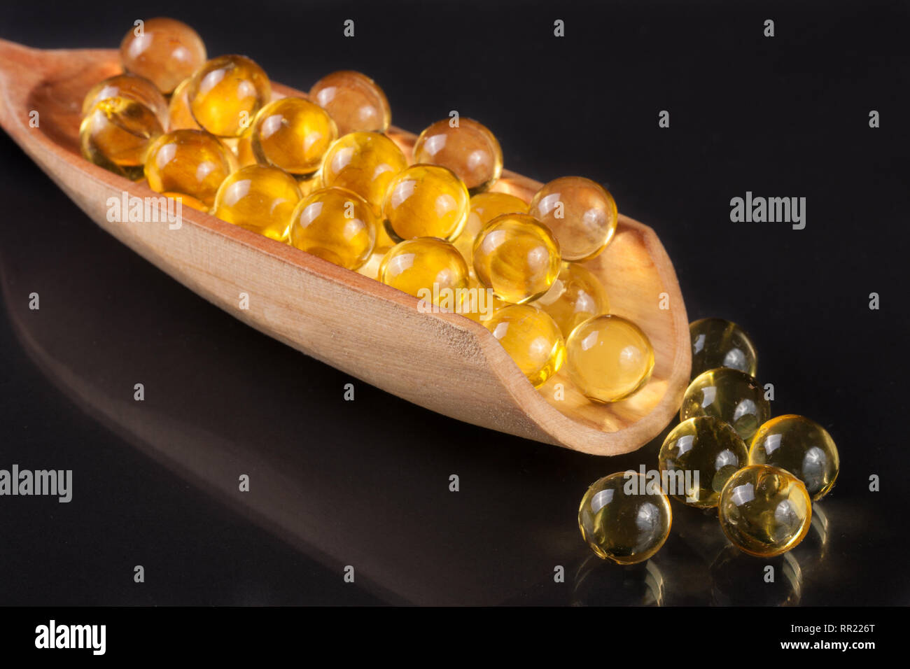 Fischöl Kapseln in eine hölzerne Schaufel auf einem dunklen Hintergrund Stockfoto