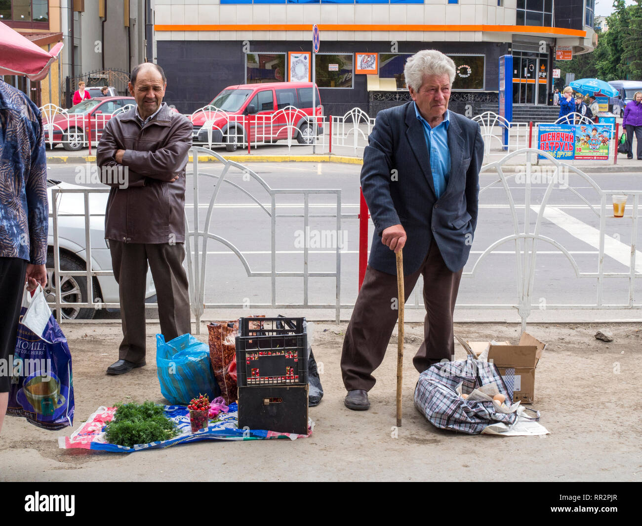 Männer verkaufen Startseite angebautes Obst und Gemüse und Eier auf einer Straße in Kamjanez-podilskyj, Ukraine. Stockfoto