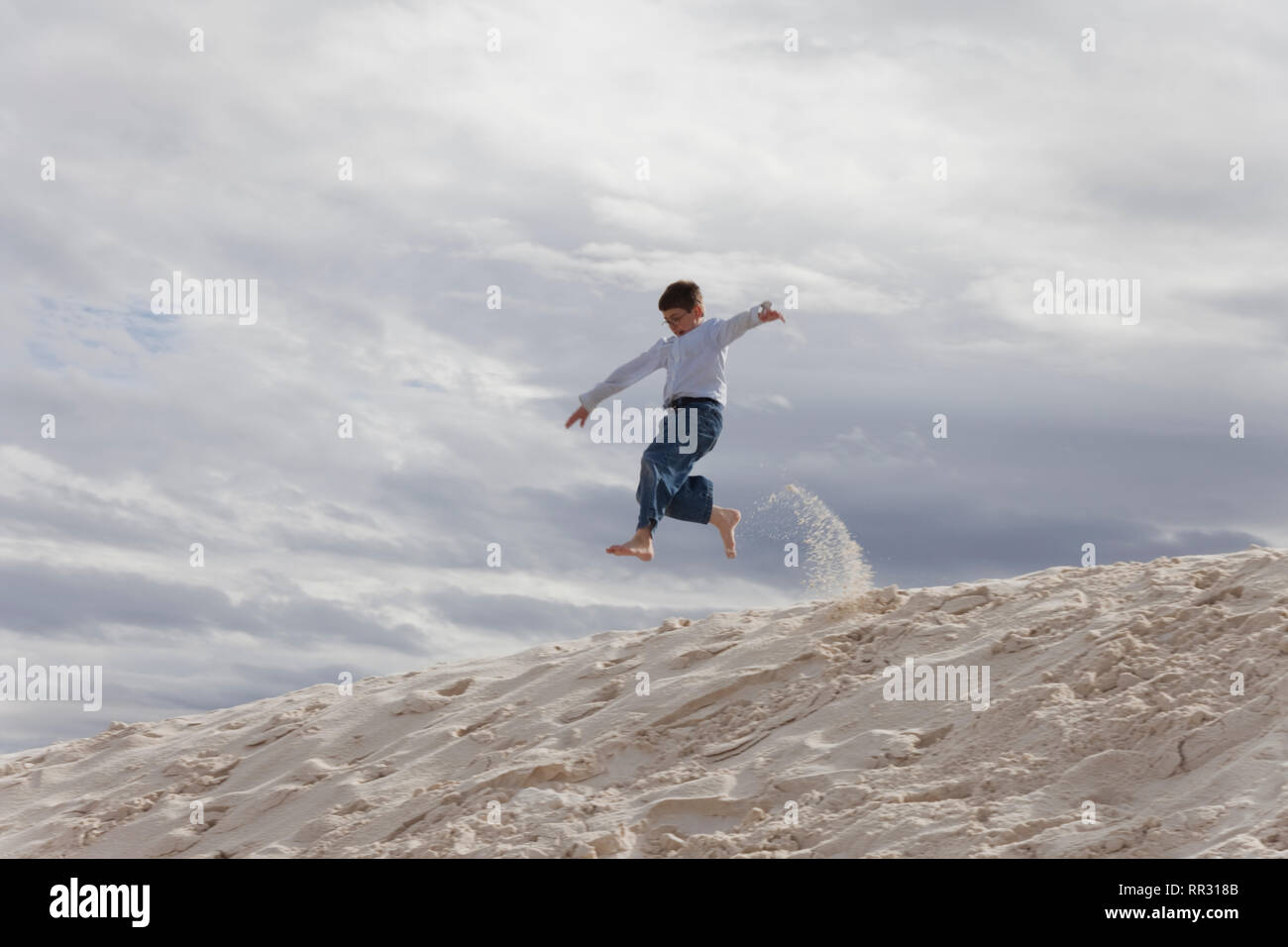 Jungen springen Sanddüne Stockfoto