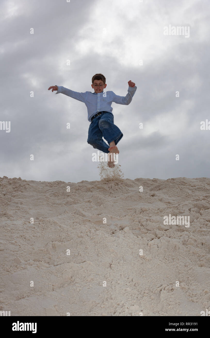 Junge springt in Sanddüne Stockfoto