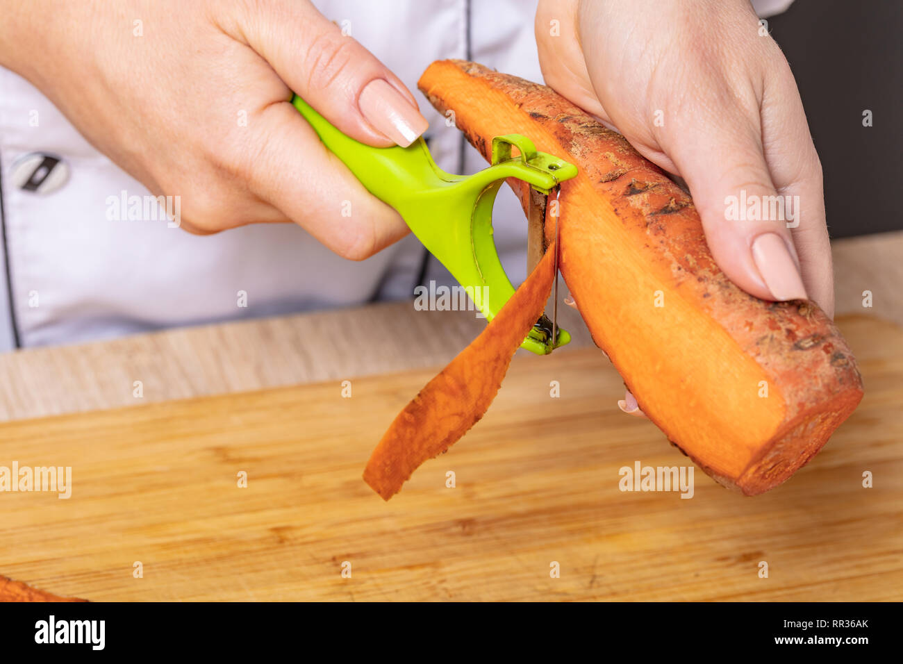 Cook reinigt Karotten, Gemüse zum Kochen vorbereiten Stockfoto