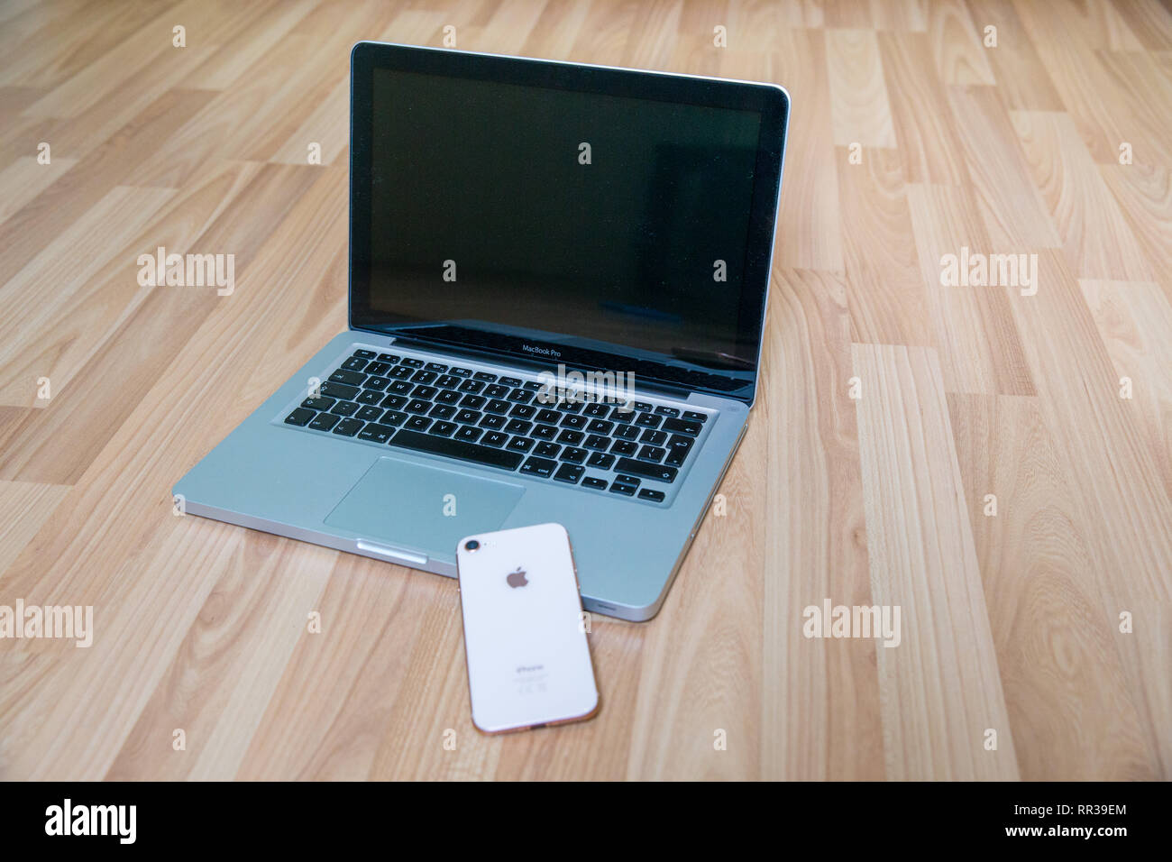 Stadt Riga, Lettland. Apple gold Handys und Mac Book Pro im Wohnzimmer. Alte hölzerne Textur. Urban home design 2019. Stockfoto