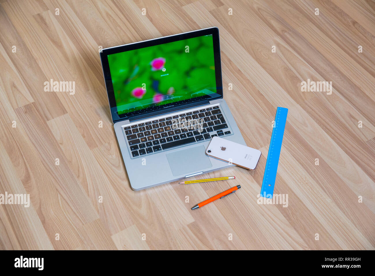 Stadt Riga, Lettland. Apple gold Handys und Mac Book Pro im Wohnzimmer. Alte hölzerne Textur und Stift. Urban home design 2019. Stockfoto