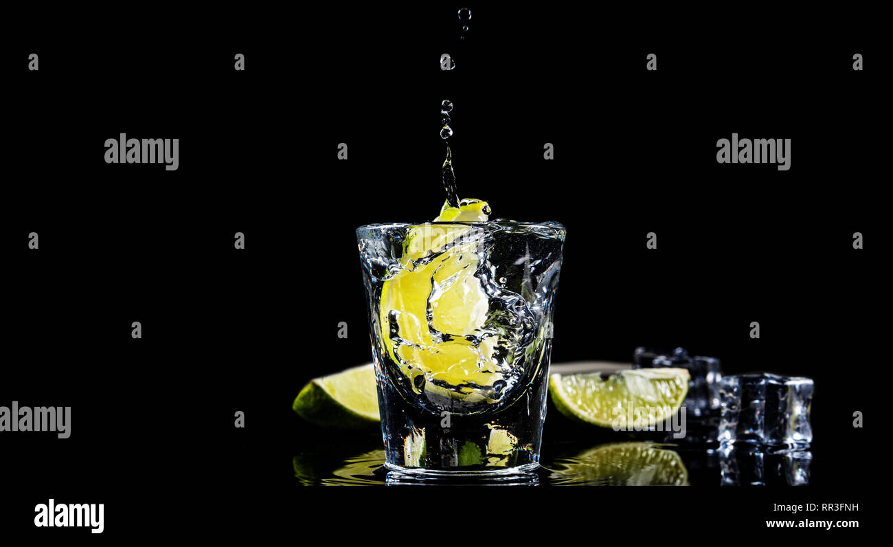 Mexikanische traditionelle Tequila splash Kalk auf schwarzen Hintergrund mit Ice Cube. Stockfoto