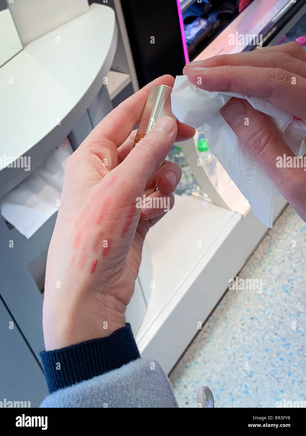 POV Frau Reinigung roten Lippenstift liner Zeichenstift nach der Prüfung Farbe auf der Rückseite der Hand Stockfoto
