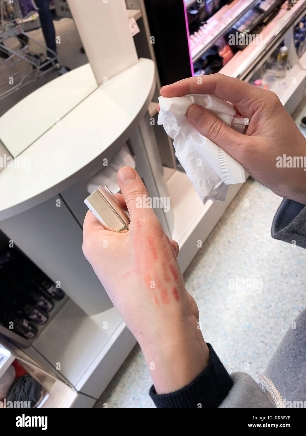 Frau Reinigung roten Lippenstift liner Zeichenstift nach der Prüfung Farbe auf der Rückseite der Hand Stockfoto
