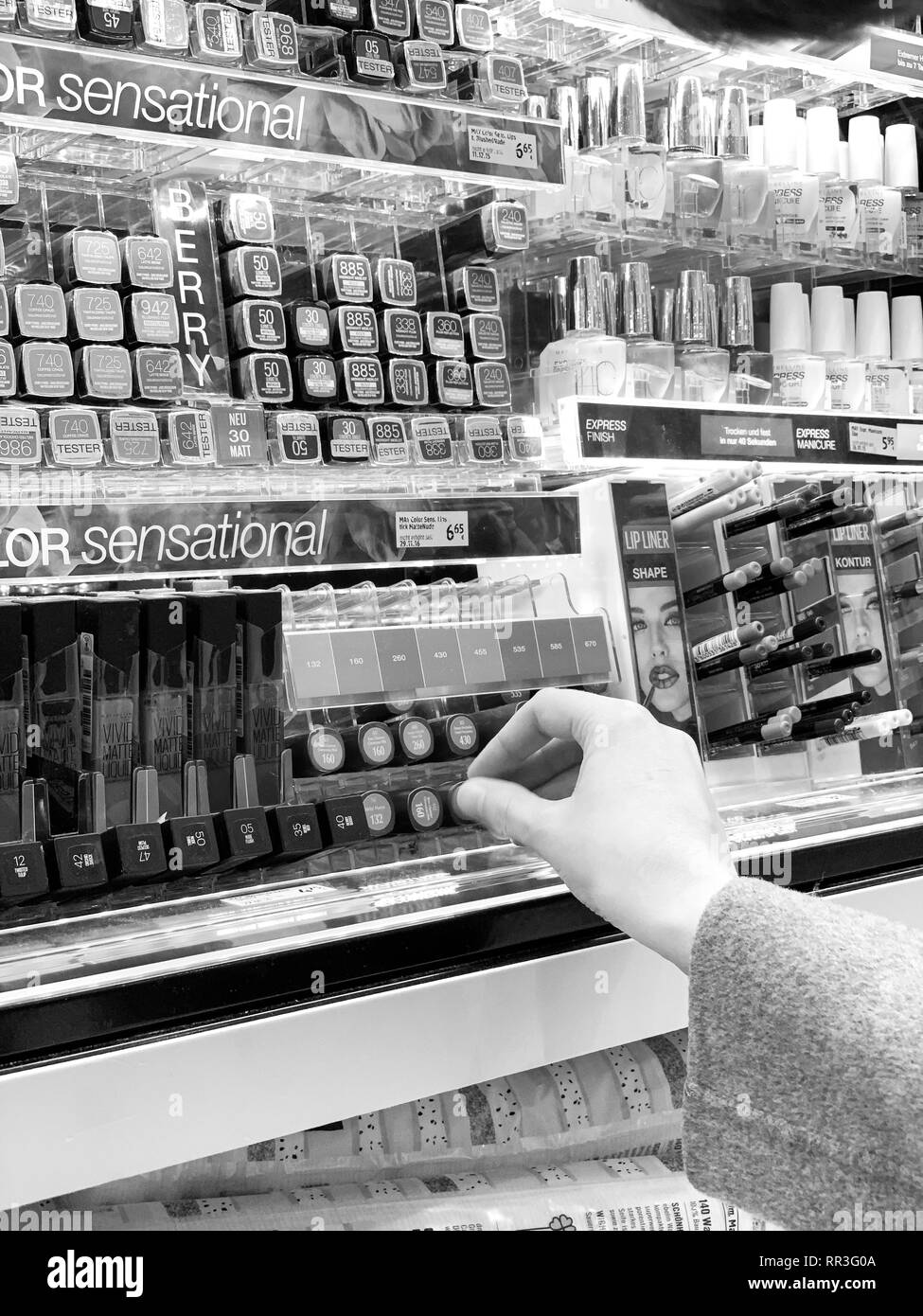 München, Deutschland - 27.Oktober 2018: die Frau in der Kosmetik kaufen Red store Lippenstift liner zeichenstift zwischen der Vielzahl Wahl schwarz und weiß Stockfoto