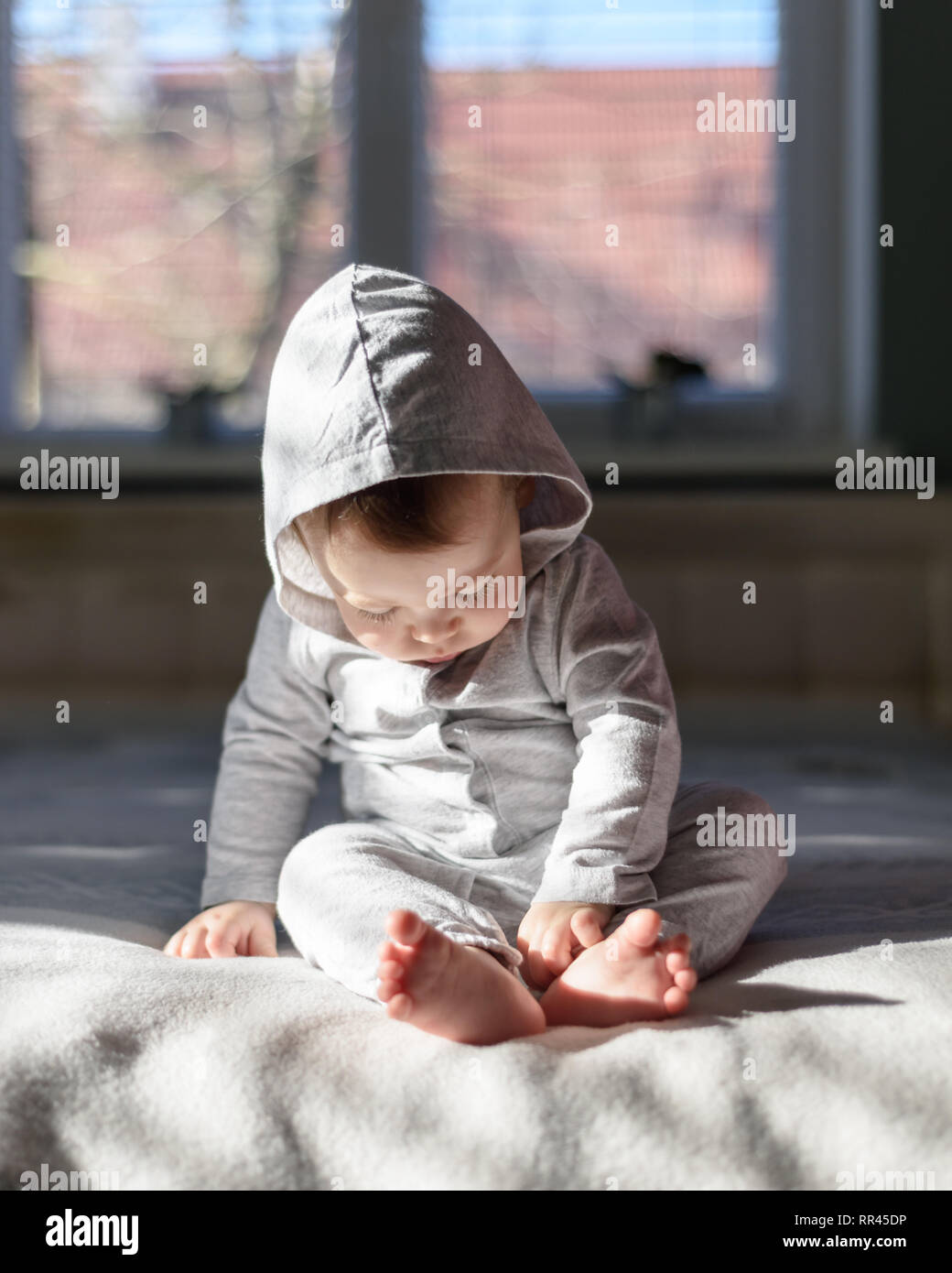 Happy Baby boy in grauen Schlafanzug auf Bett in seinem Zimmer Stockfoto