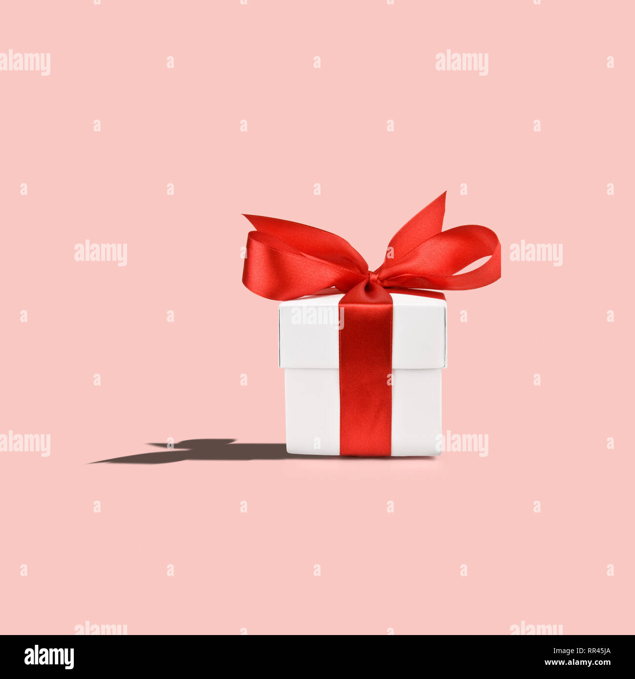 Weiß Geschenkbox mit roter Schleife auf rosa Hintergrund Stockfoto