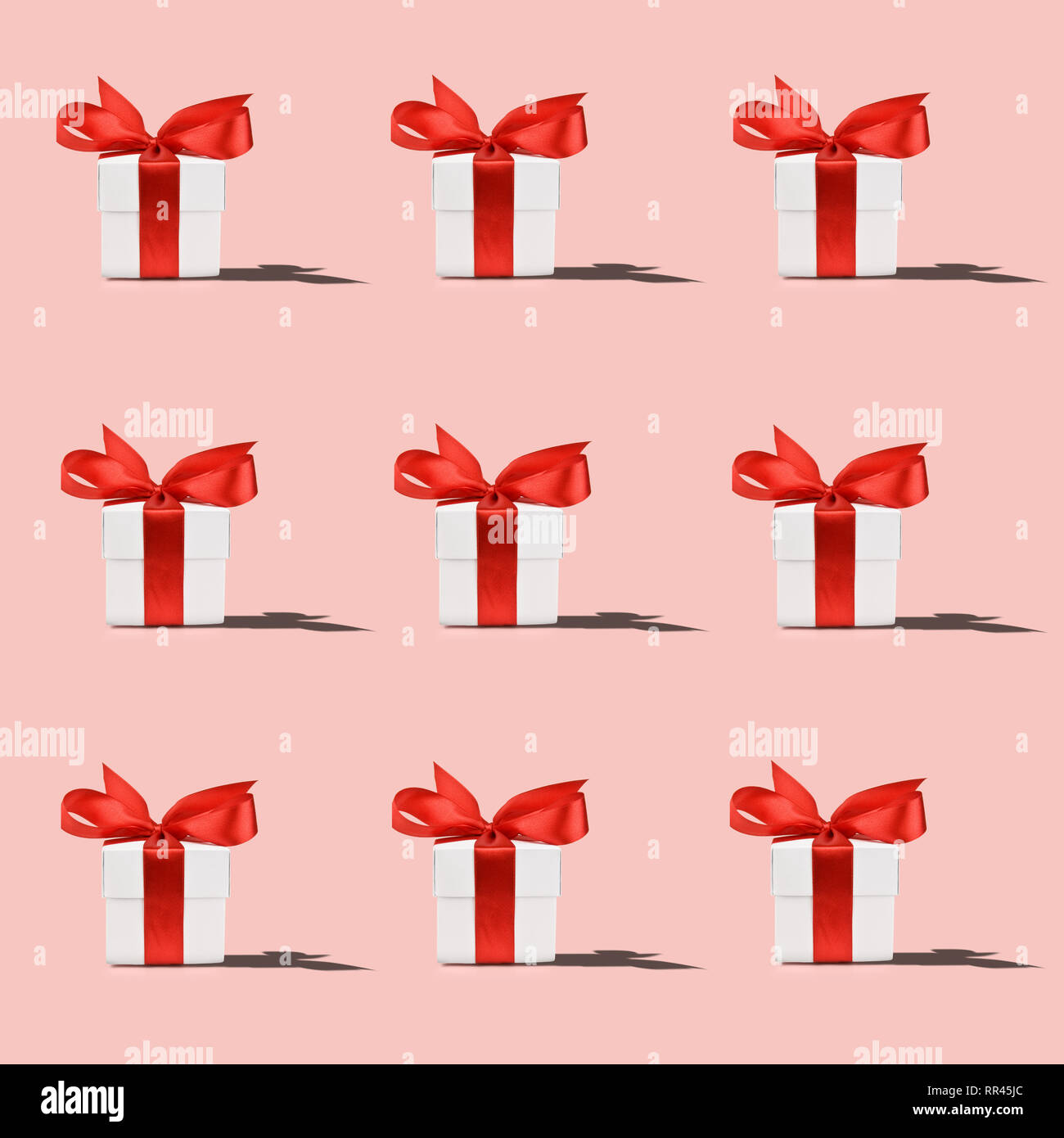 Muster der weißen Geschenkbox mit roter Schleife auf rosa Hintergrund Stockfoto