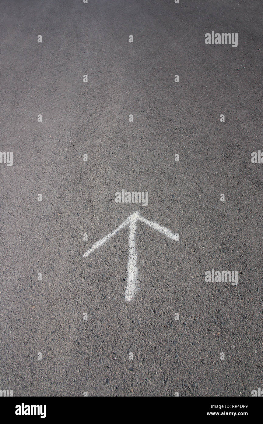 Pfeil in weiß gezeichnet auf dem grauen Asphalt der Straße, und Raum für Texte oder Zeichnungen, (Kopie) Stockfoto