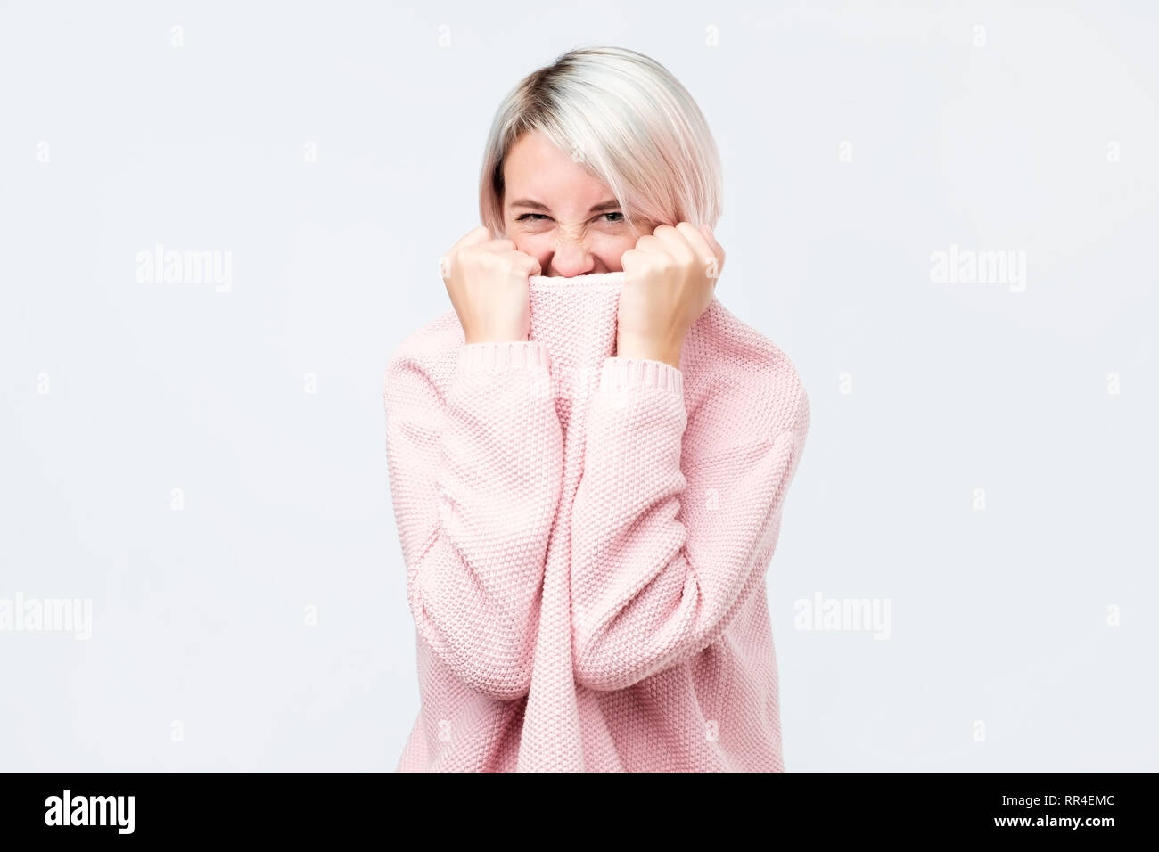 Ein Mädchen mit einer sozialen Phobie verbirgt ihr Gesicht in einen Pullover. Stockfoto