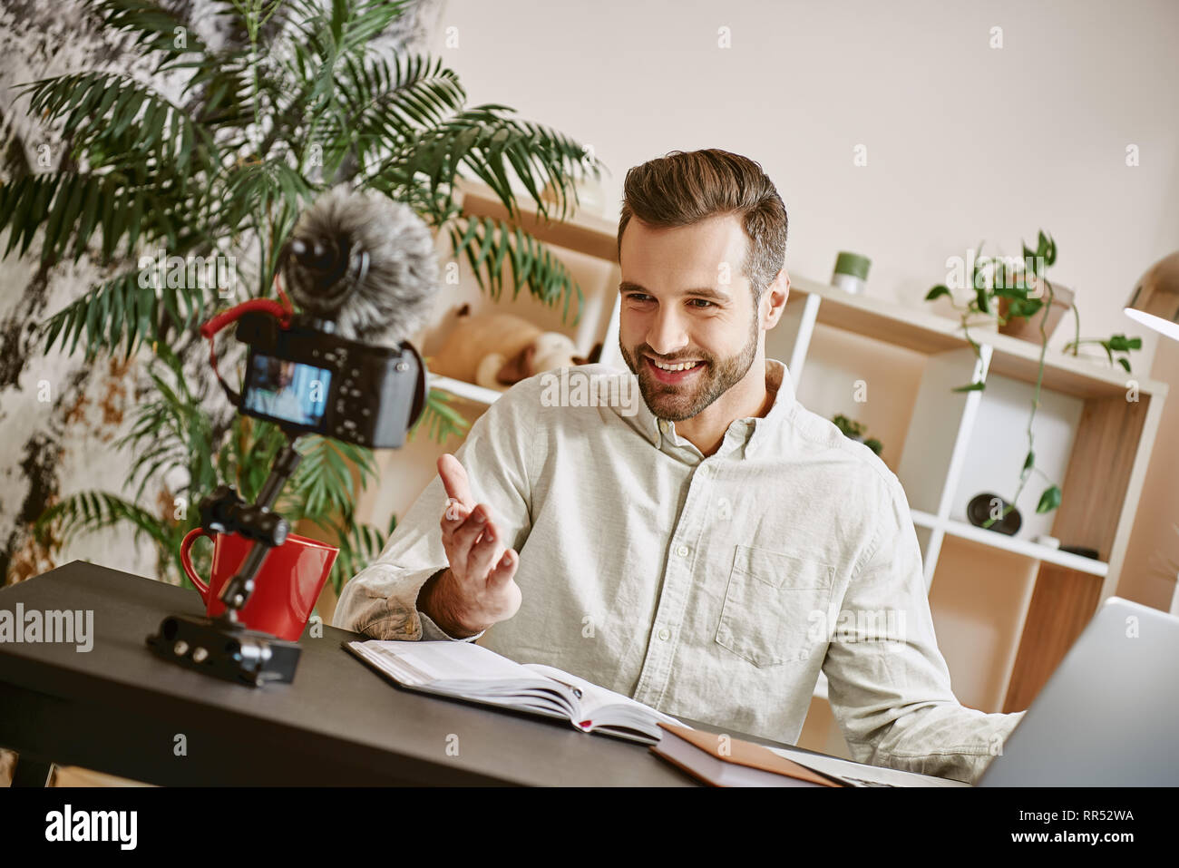 Ich bin so glücklich! Fröhlicher junger männlichen Blogger, einen neuen Inhalt für seinen Vlog mit Stativ montiert Digitalkamera. Inhalt. Video. Blogger Stockfoto