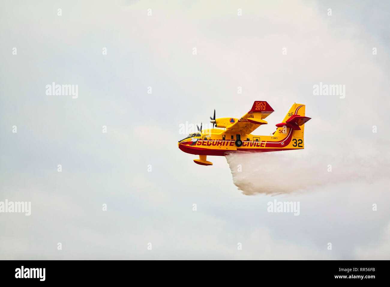 In LE BOURGET, Frankreich - 24. Juni 2017. Kleine gelbe rote Wasserflugzeug Wasserflugzeug fliegen in den Himmel mit Wolken droping Wasser auf der Internationalen Luft- und Stockfoto