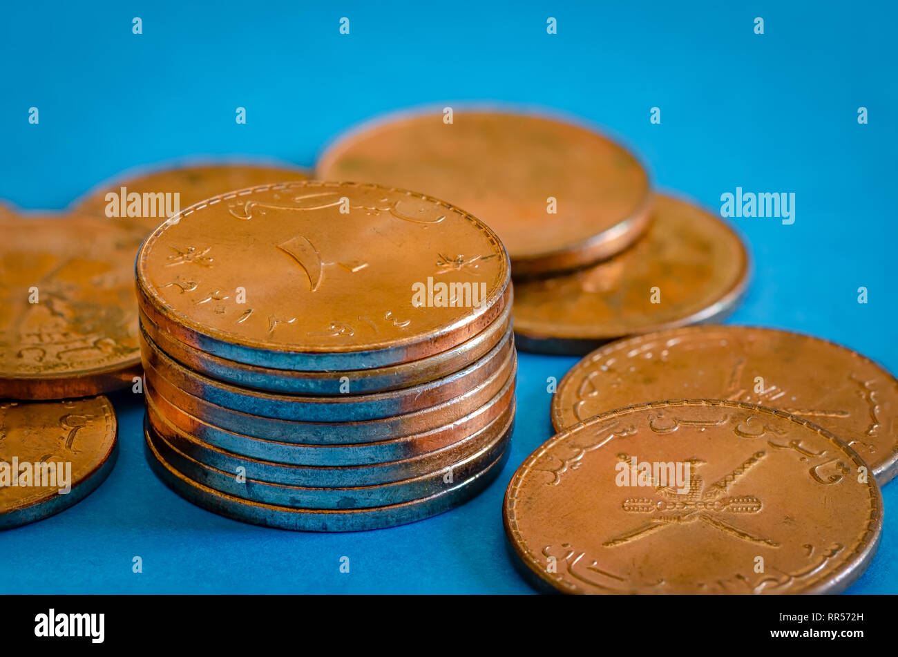 Nahaufnahme von 10 Baiza Bronze Münzen auf blauem Hintergrund. Sultanat Oman Währung. Stockfoto