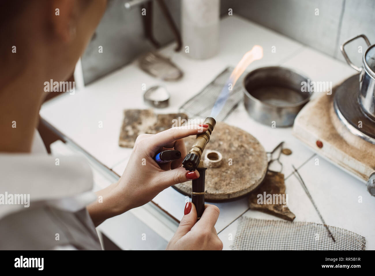 Arbeiten mit einem Brand. Weibliche Juwelier Hände Löten und Schweißen Silber Ring an ihrem Schmuck Werkstatt. Business. Schmuck Ausstattung. Zubehör Stockfoto