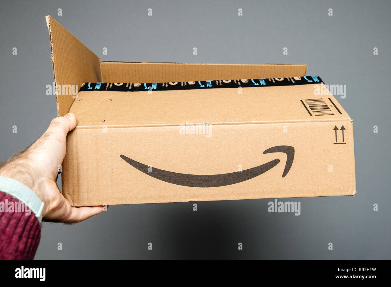 Paris, Frankreich, 23.Februar 2019: Mann, gegen den grauen Hintergrund  Amazon Prime Karton mit Smile Amazon Pfeil Schriftzug geöffnet  Stockfotografie - Alamy