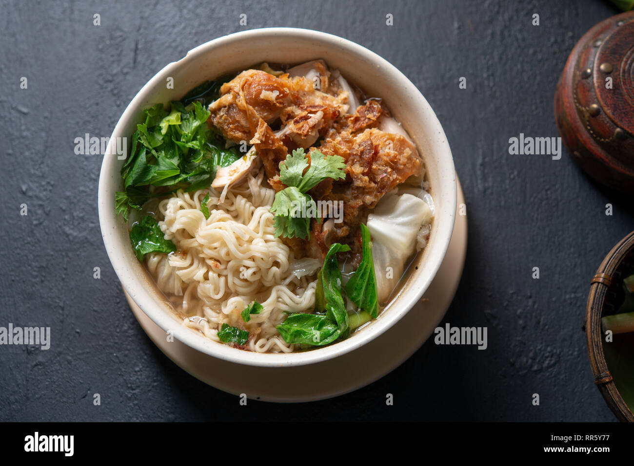 Asiatische Ramen Nudeln Suppe und Hühnchen in der Schüssel auf dunklem Hintergrund. Ansicht von oben flach. Stockfoto