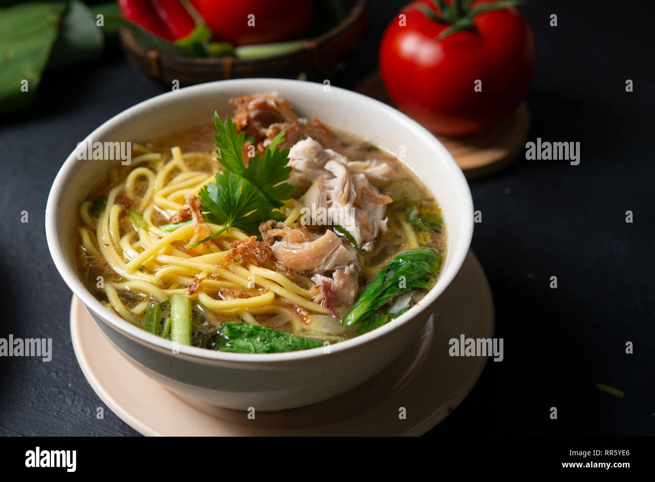 Asiatische Suppe, Nudeln und Huhn in Schüssel auf dunklem Hintergrund. Stockfoto