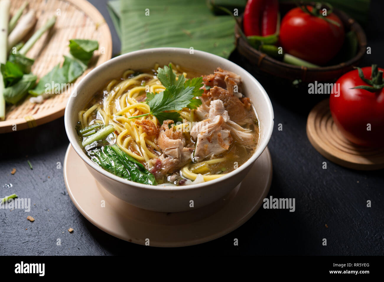 Asiatische Suppe, Nudeln und Huhn in Schüssel auf dunklem Hintergrund. Stockfoto