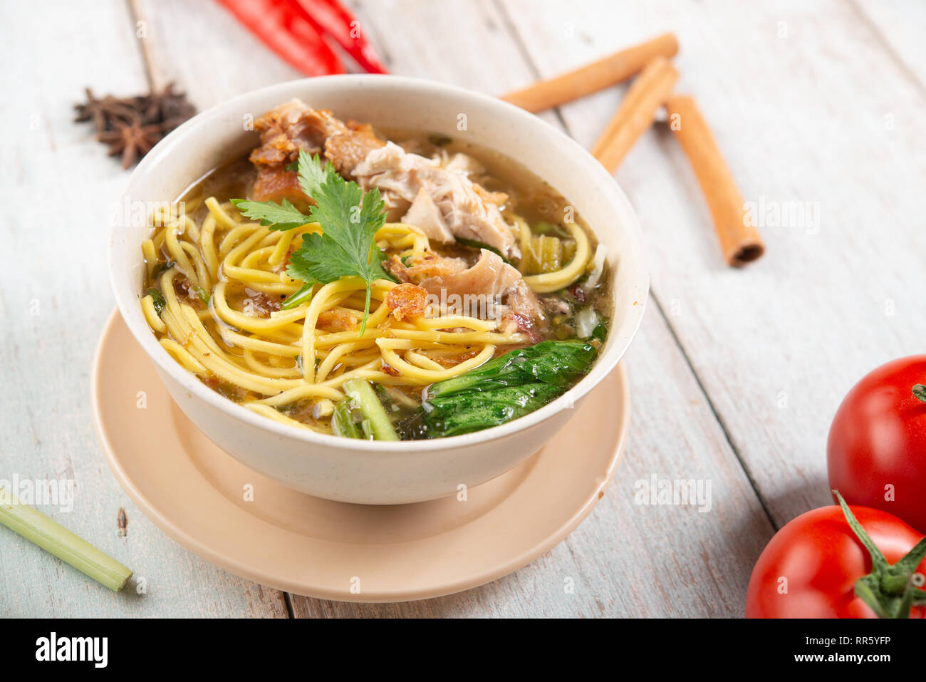 Asiatische Suppe, Nudeln und Huhn in Schüssel auf Holz- Hintergrund. Stockfoto