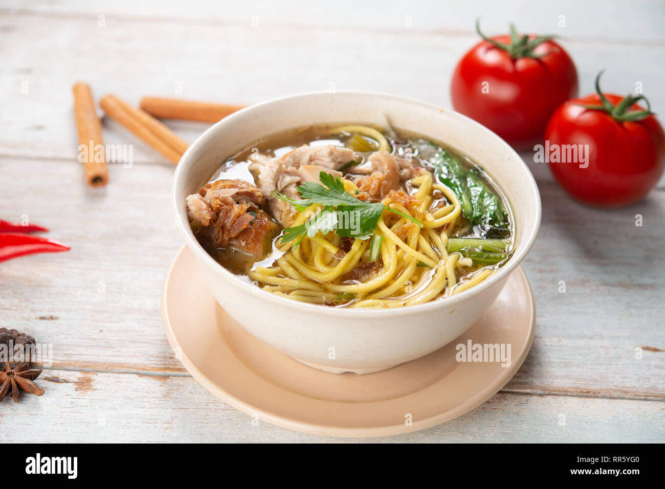 Asiatische Suppe, Nudeln und Huhn in Schüssel auf Holz- Hintergrund. Stockfoto