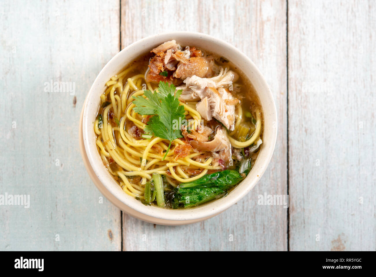 Asiatische Suppe, Nudeln und Huhn in Schüssel auf Holz- Hintergrund. Ansicht von oben flach. Stockfoto