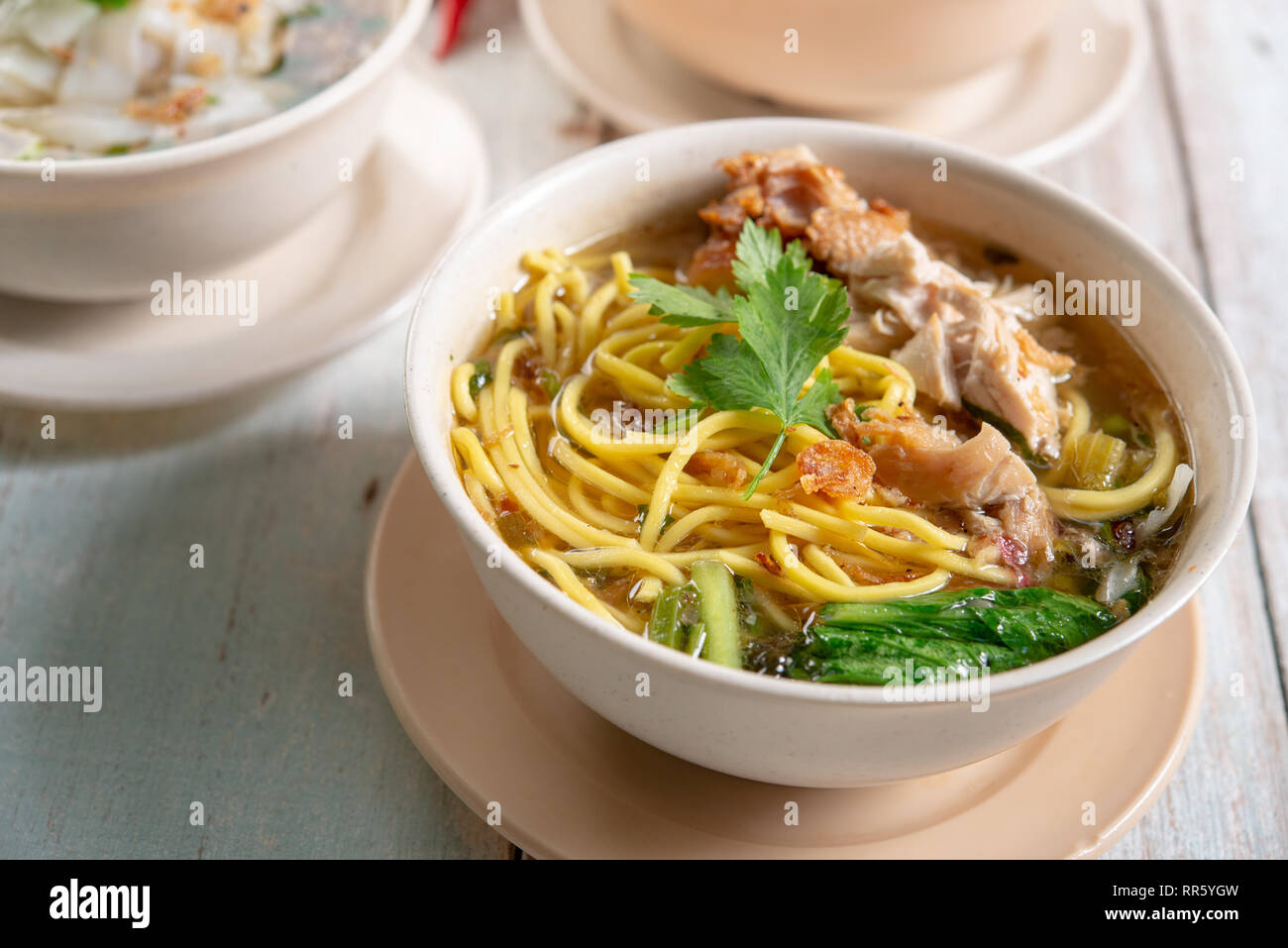 Asiatische Suppe, Nudeln und Huhn in Schüssel auf Holz- Hintergrund. Stockfoto