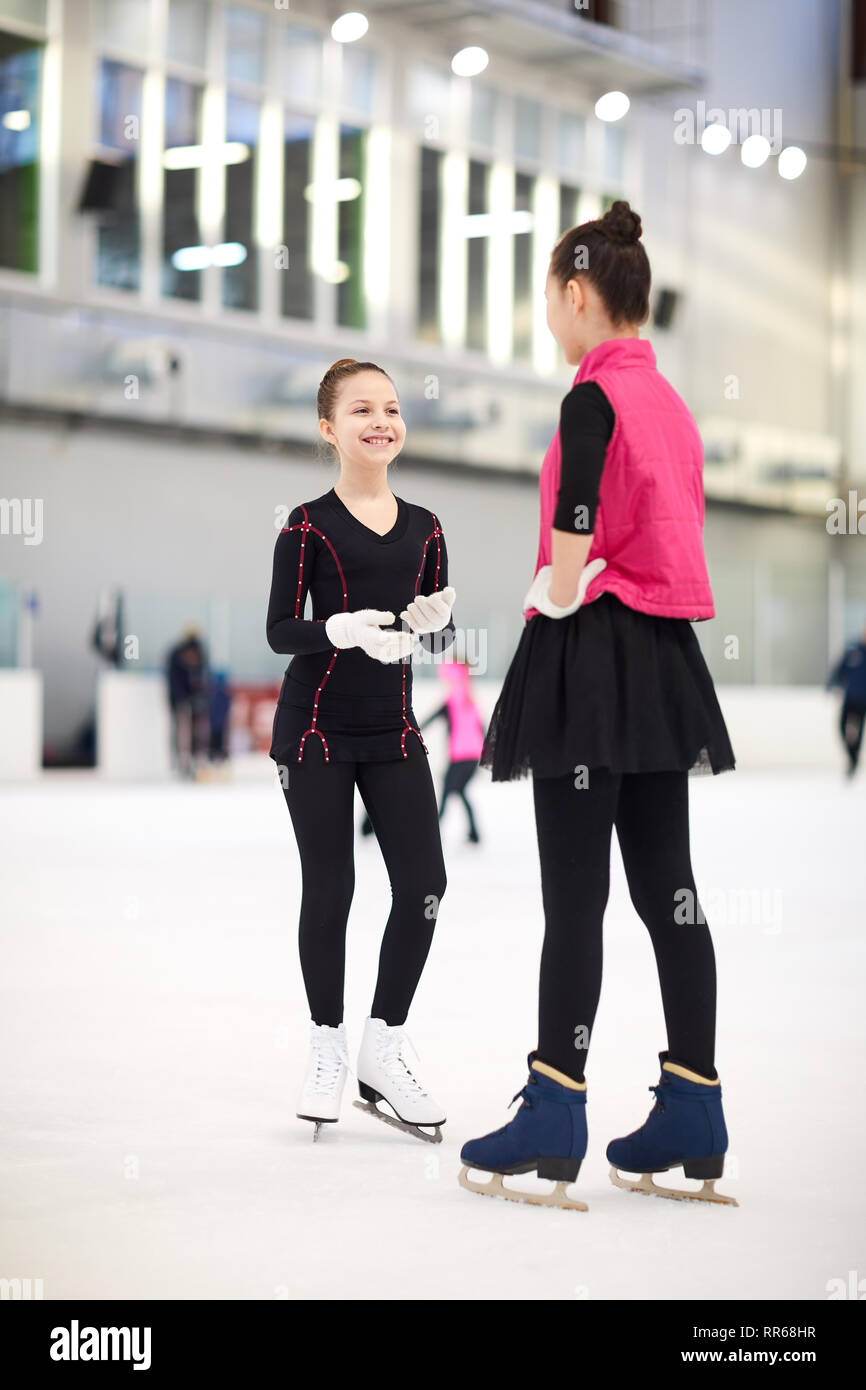 In voller Länge Porträt von zwei Mädchen im Teenageralter Eiskunstlauf auf der Eisbahn und fröhlich plaudernd in der Pause, kopieren Raum Stockfoto