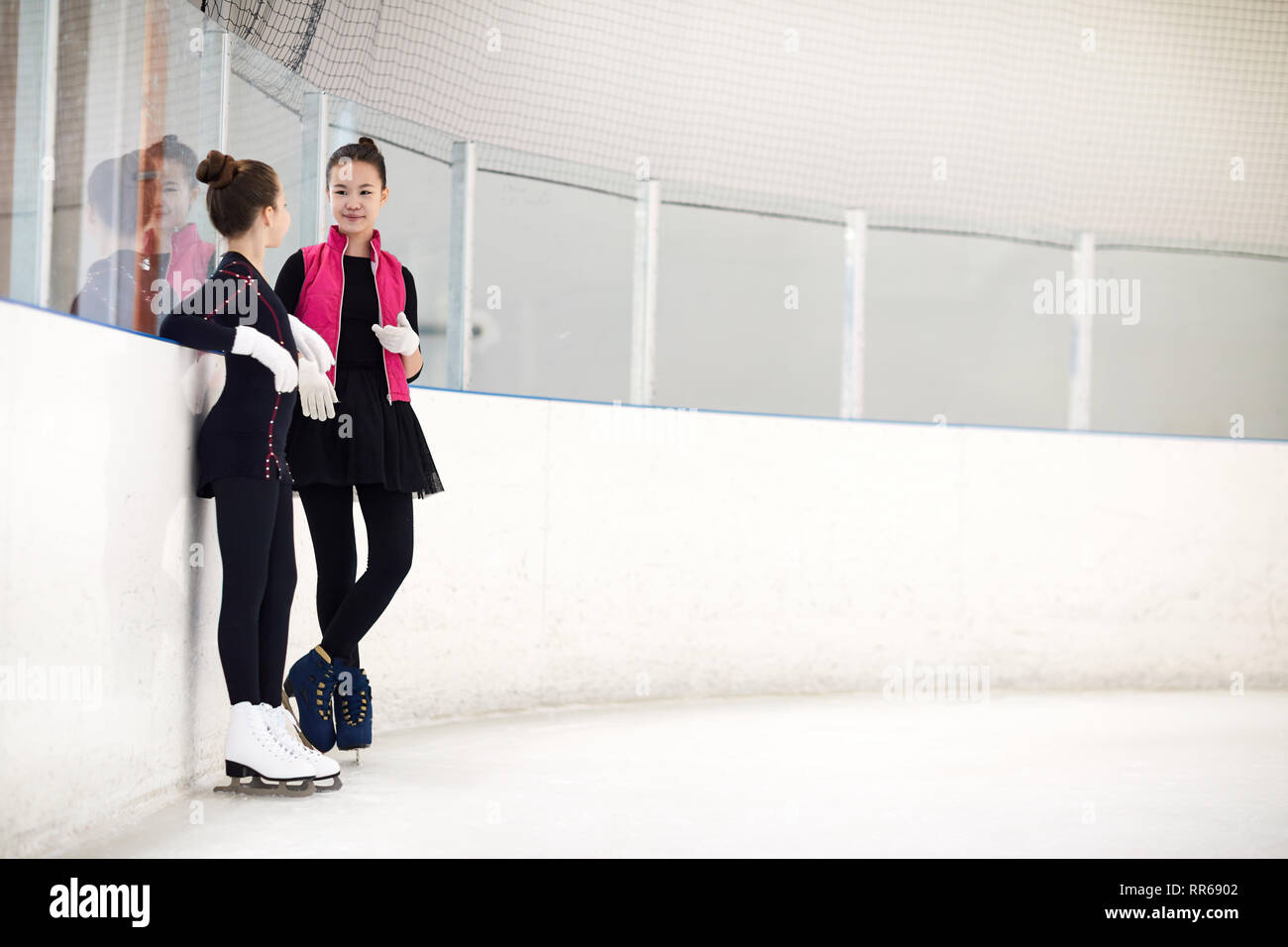 In voller Länge Porträt von zwei jungen Mädchen Chatten in Eisbahn beim Eiskunstlauf Praxis, kopieren Raum Stockfoto