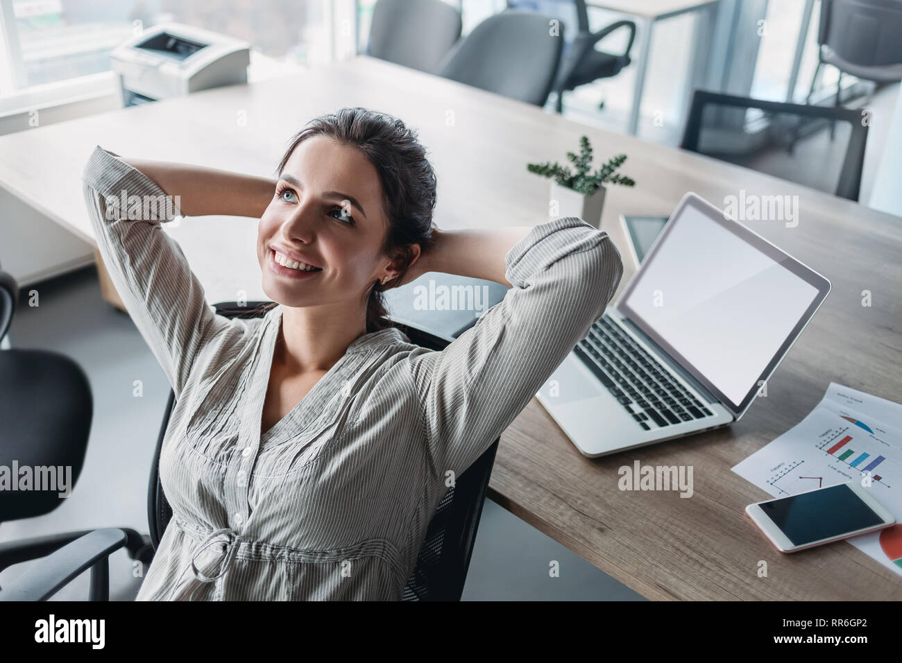 Schöne dunkelhaarige Frau träumt mit offenen Augen in den Bürostuhl. Geschäftsfrau fühlt sich entspannt nach einem anstrengenden Arbeitstag. Weibliche lehnte sich zurück in Chai Stockfoto
