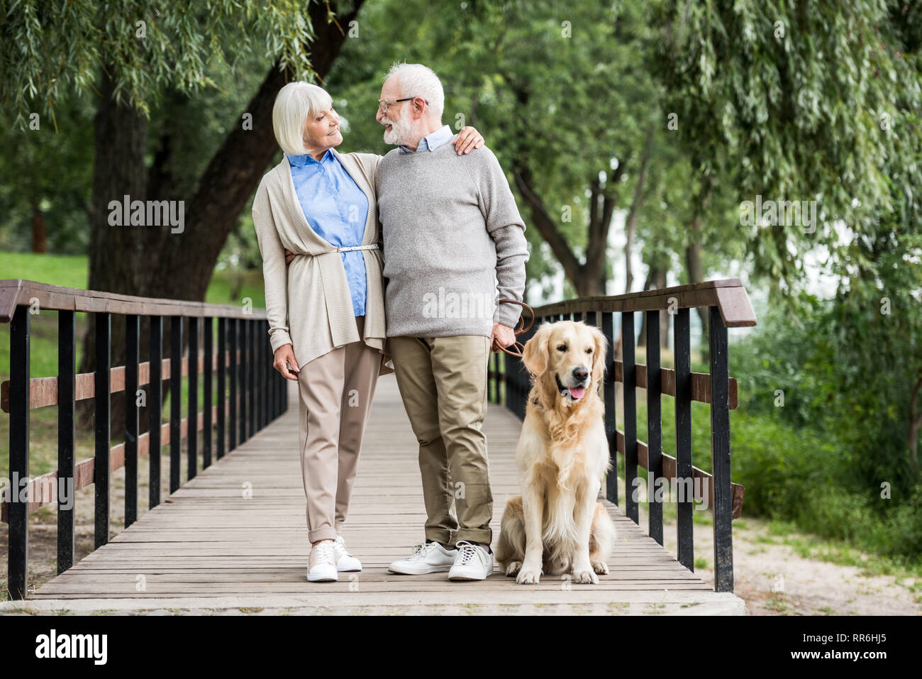 Lächelnd senior Paar umarmen beim Wandern mit Hund im Park Stockfoto