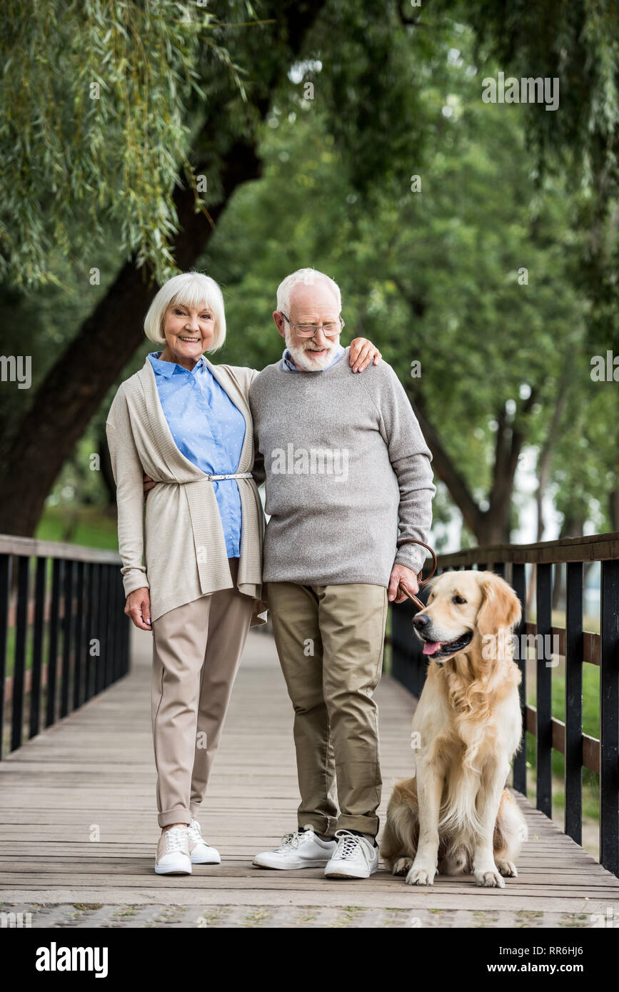 Gerne älteres Paar umarmen beim Gehen mit freundlicher Hund im Park Stockfoto