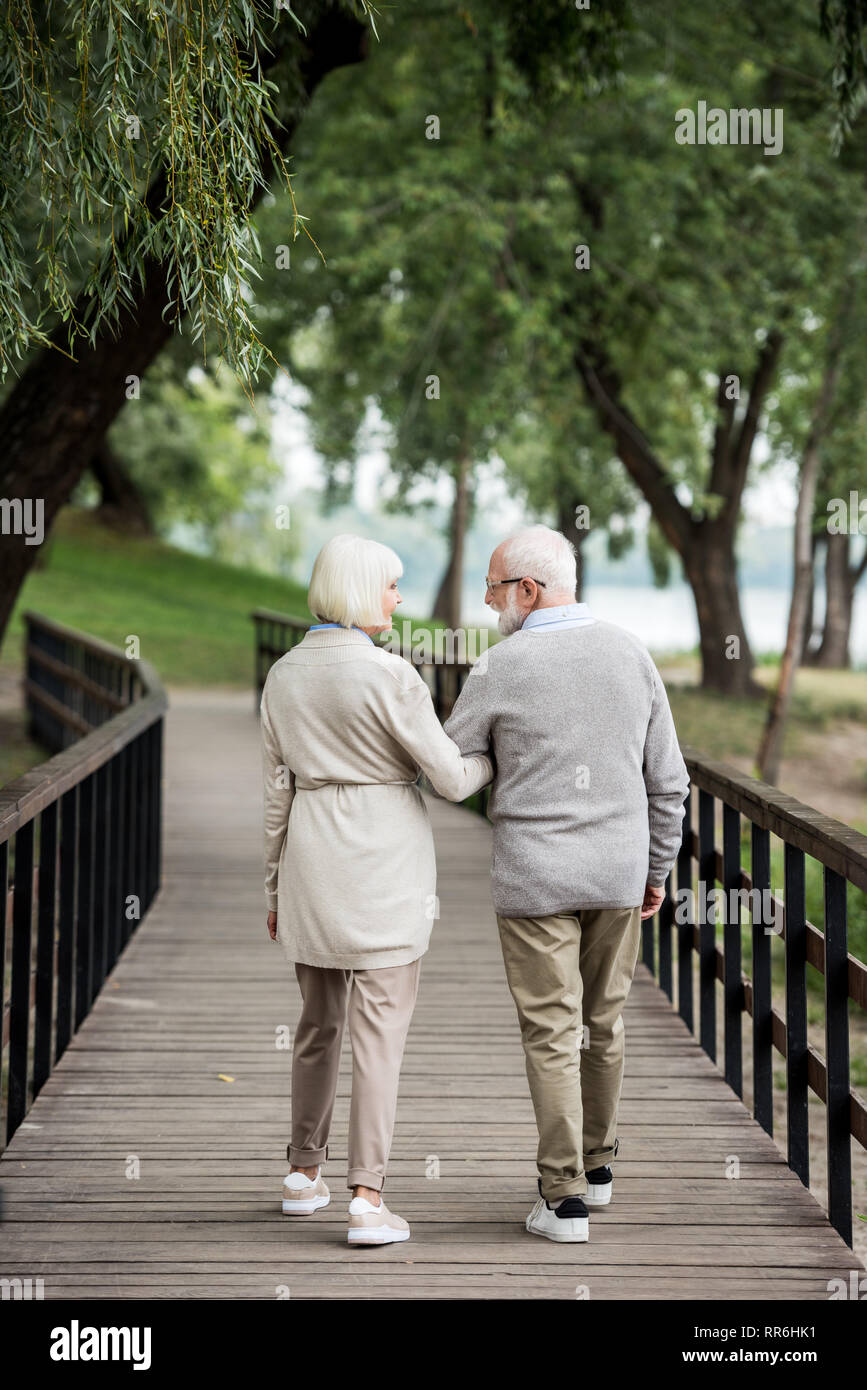 Älteres Ehepaar miteinander reden, während man über eine Holzbrücke in Park Stockfoto