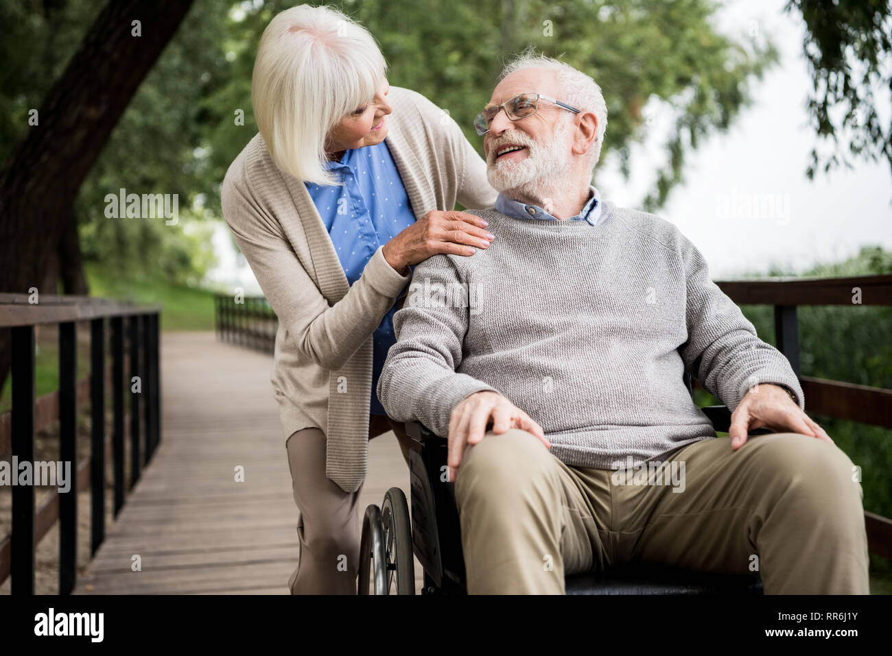 Schöne ältere Frau mit Mann im Rollstuhl im Park Stockfoto