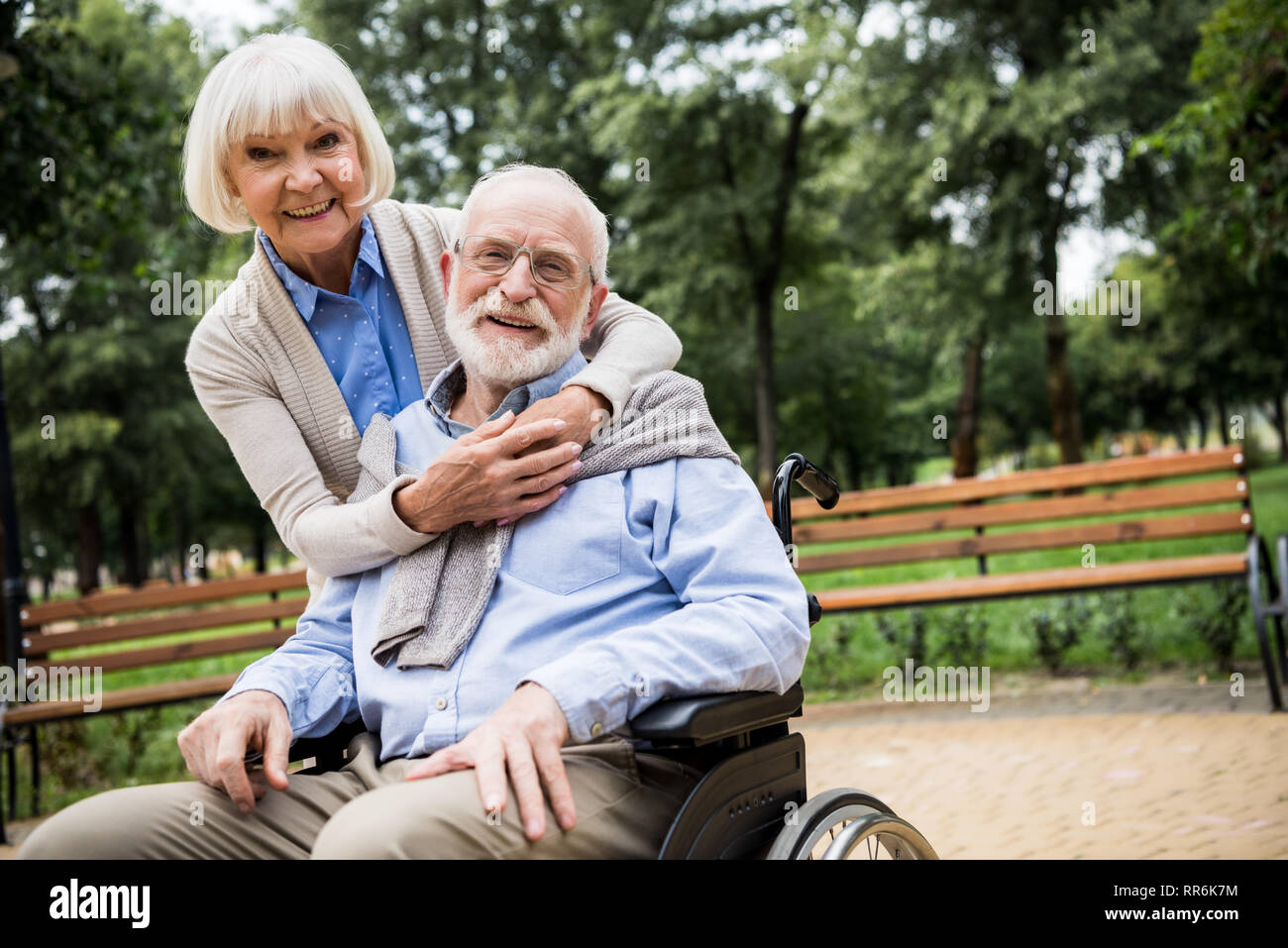 Lächelnde ältere Frau mit Mann im Rollstuhl im Park Stockfoto