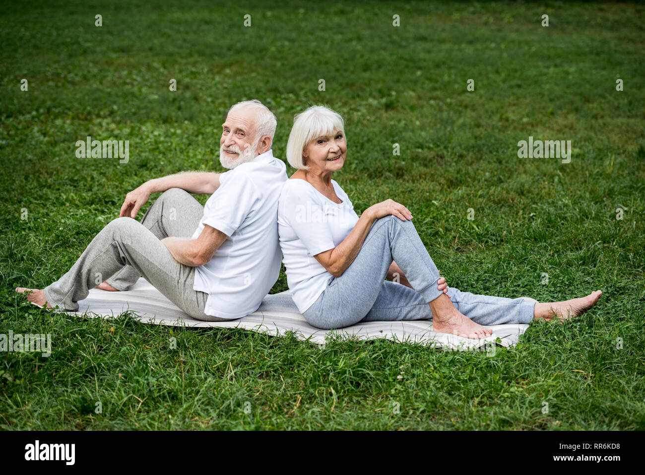 Lächelnd senior Paar entspannende Yoga Matten in Park Stockfoto