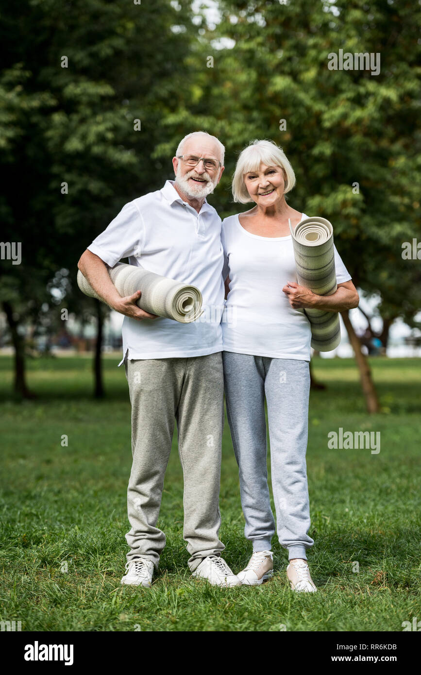 Gerne älteres Paar umarmen beim Stehen mit Fitness Matten in Park Stockfoto