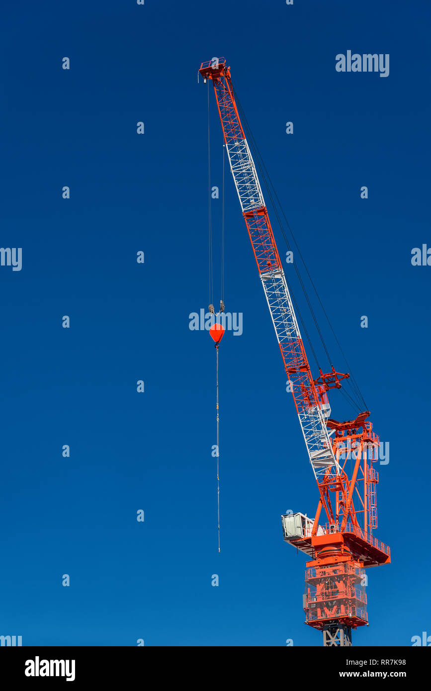 Bau fester Kran mit Kabine und Haken bei der Arbeit vor blauem Himmel (mit Kopie Raum) Stockfoto