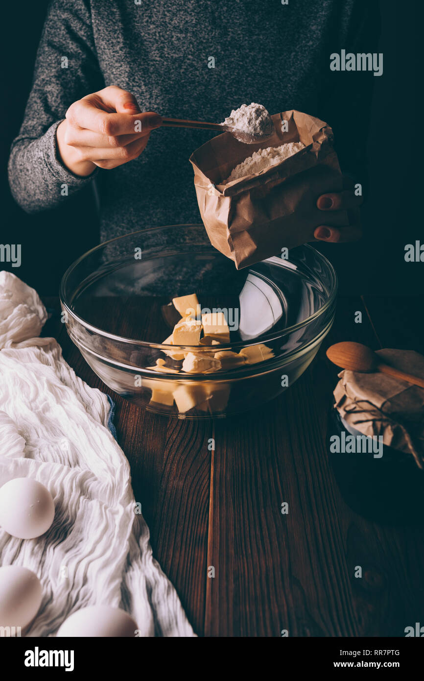 Nahaufnahme der weiblichen Hand Tasche und gehäuften Löffel Mehl in Schüssel mit gewürfelte Butter Teig gießen für Kreis zu machen. Frau kochen Hausgemachte cak Stockfoto