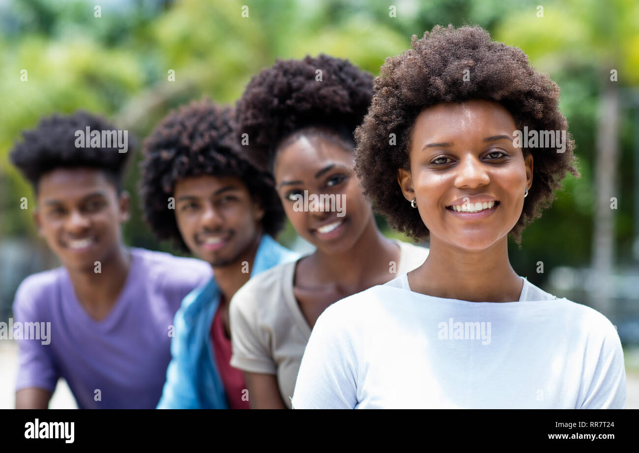 Glückliche afroamerikanische Frau mit einer Gruppe von jungen Erwachsenen, die in der Linie im Freien in der Stadt im Sommer Stockfoto