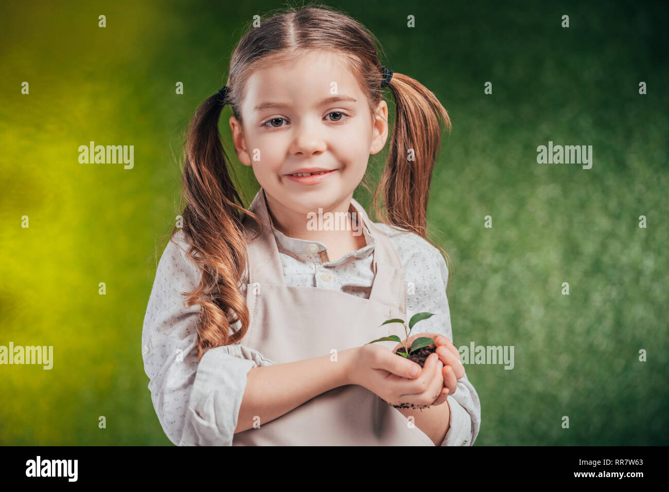Niedliche Kind halten junge grüne Pflanze auf unscharfen Hintergrund, Tag der Erde Konzept Stockfoto
