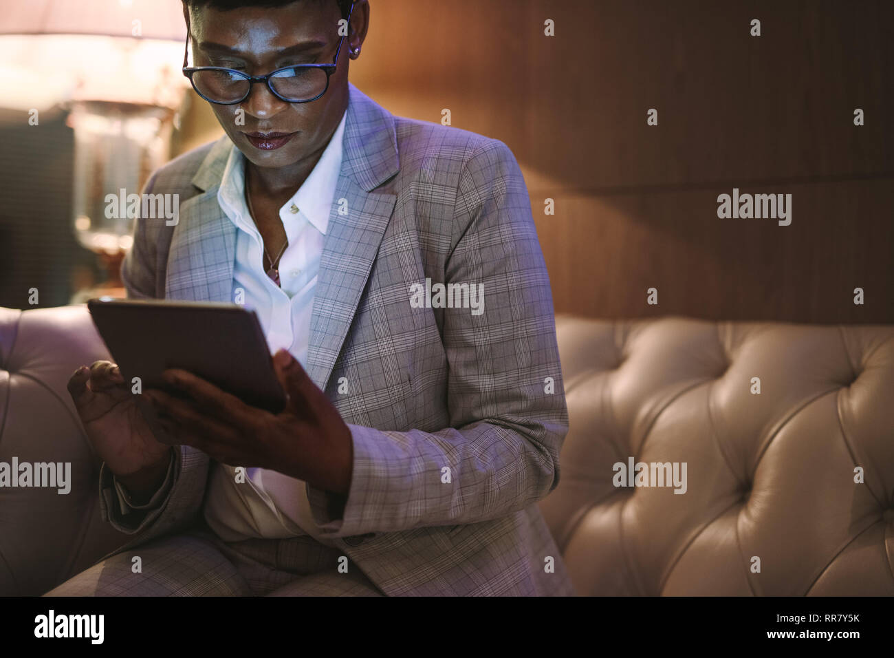 Reifen afrikanische Frau in formelle Kleidung an der Hotelrezeption mit digitalen tablet Couch sitzen. Weibliche CEO auf Geschäftsreise mit Tablet-PC im Hotel Lob Stockfoto