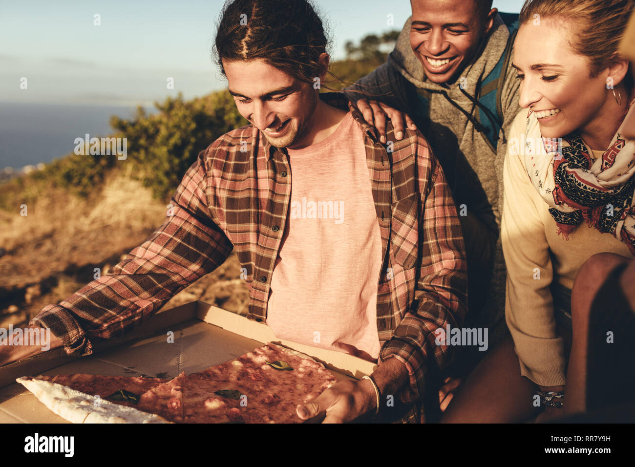 Gruppe der Wanderer in Pizza. Mann mit Pizza auf Mountain Trail mit Freunden sitzt. Stockfoto