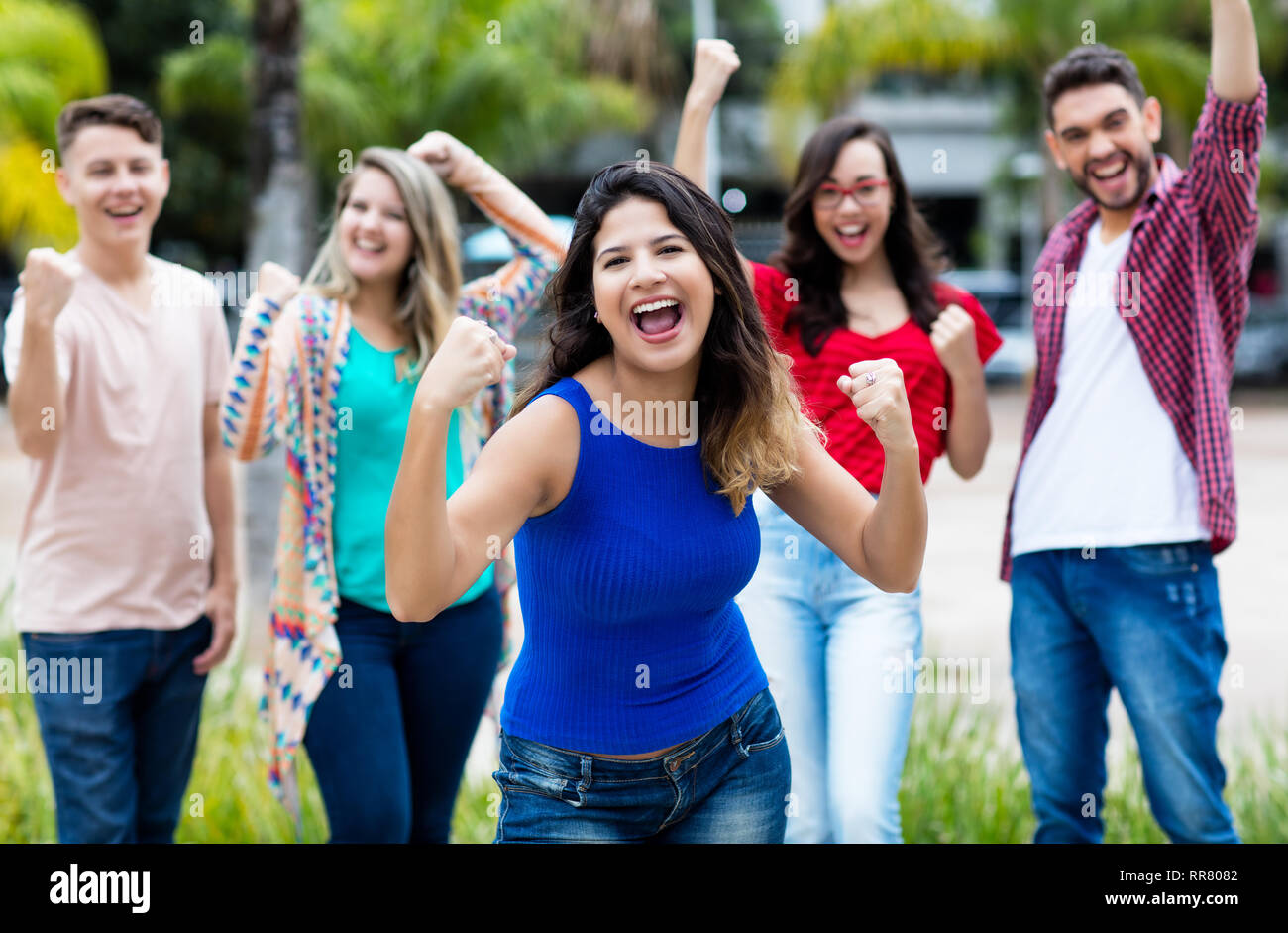 Jubelnde spanisches Mädchen mit glücklichen Gruppe von Freunden im Freien im Sommer in der Stadt Stockfoto
