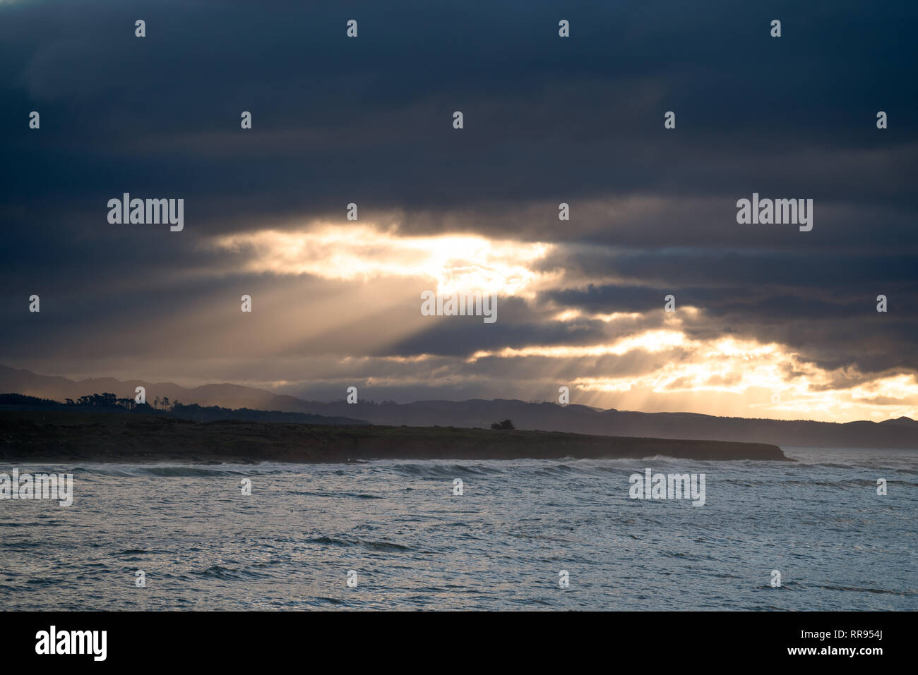 Am frühen Morgen Sonnenaufgang mit Lichtstrahlen Streaming aus einer Öffnung in der Wolken, die Beleuchtung der Küste in der Nähe von Cambria, San Simeon, Kalifornien. Stockfoto