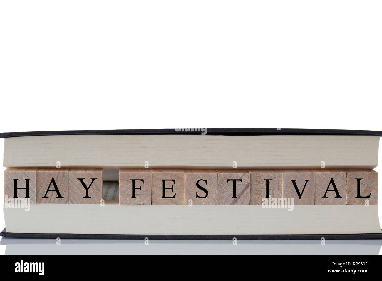 Hay Festival auf Holzblöcken in einem Buch auf einen weißen Hintergrund mit Reflexion isoliert geschrieben Stockfoto